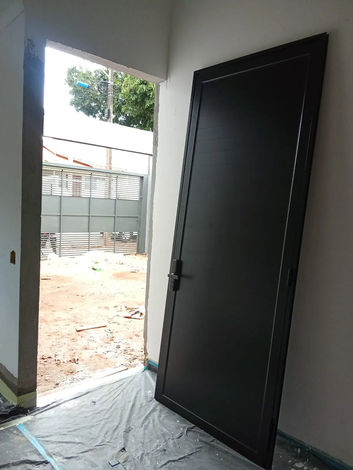 Porta de alumínio preta instalada em obra